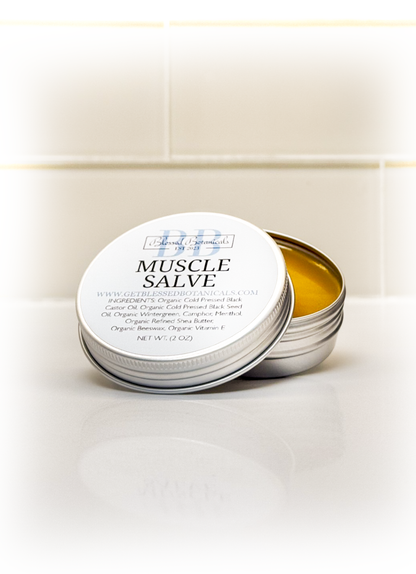 Blessed Botanicals muscle salve open tin on bathroom counter showing balm texture for topical body care
